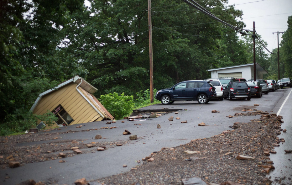 a house tobbled over off a road with other debris