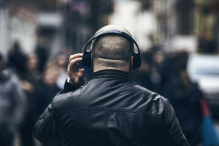 back of a man wearing headphones and a leather jacket