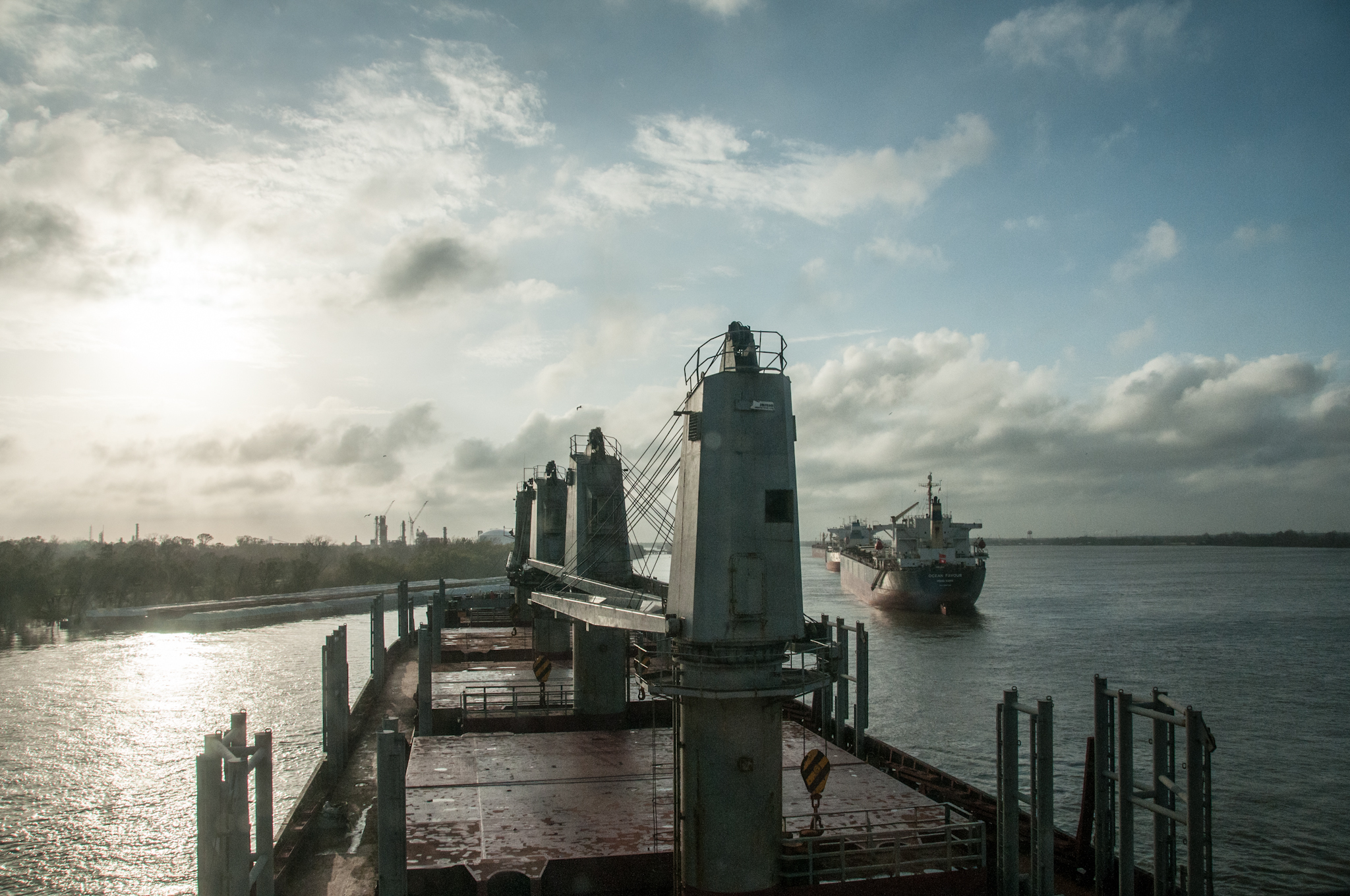 large boats on a wide expanse of water with a sun low in the sky