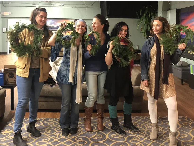 a group of women smiling and showing off wreaths