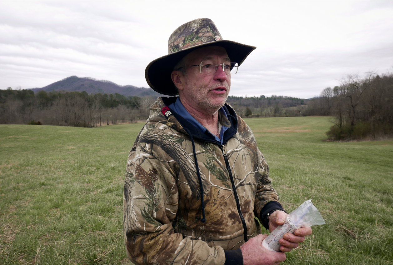 man wearing camo clothing standing in an open field