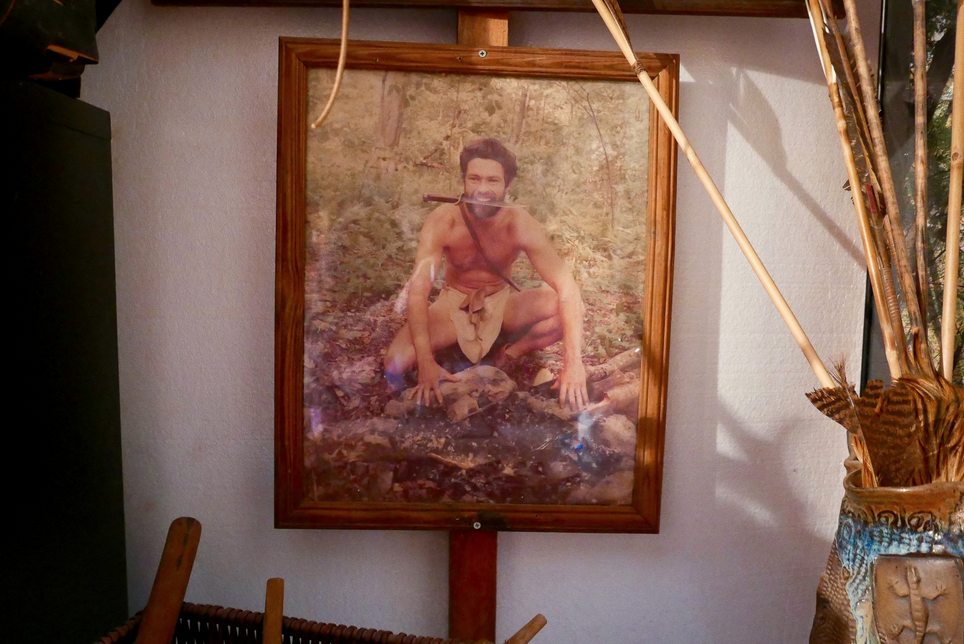 photo of a shirtless man crouched in the wilderness