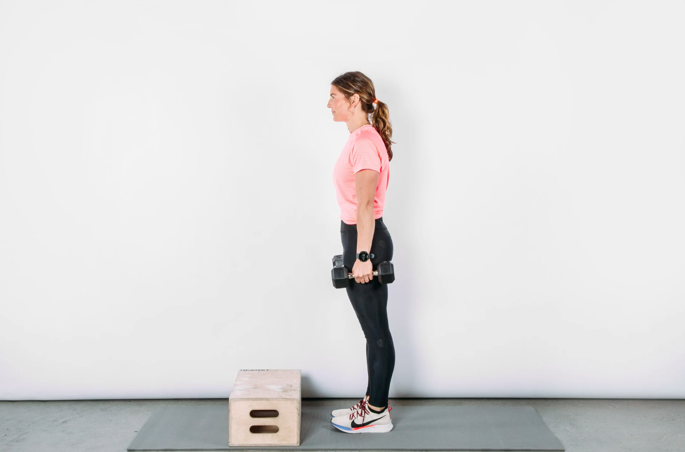 person standing holding weights in front of a small box