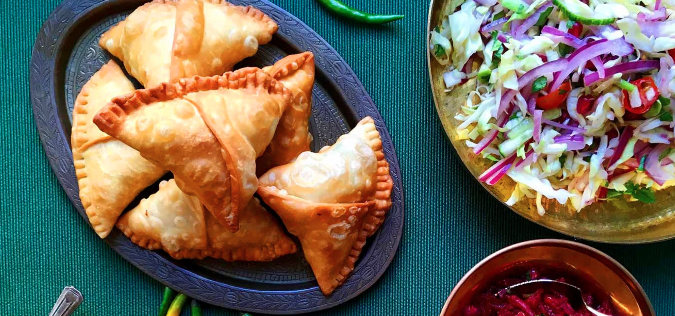 a plate of samosas next to a salad