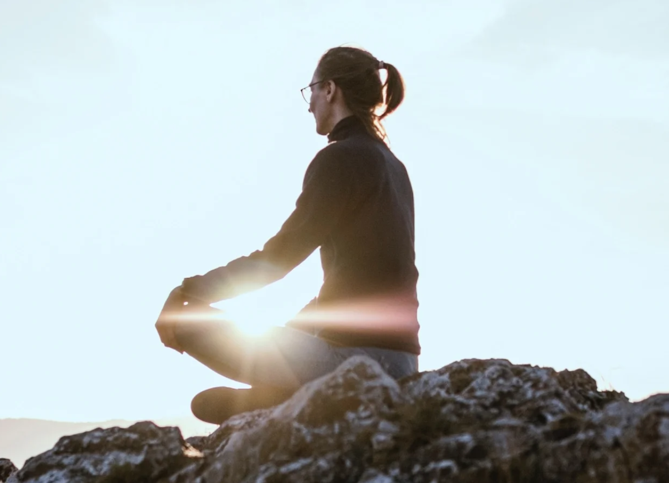 person meditating on a rock