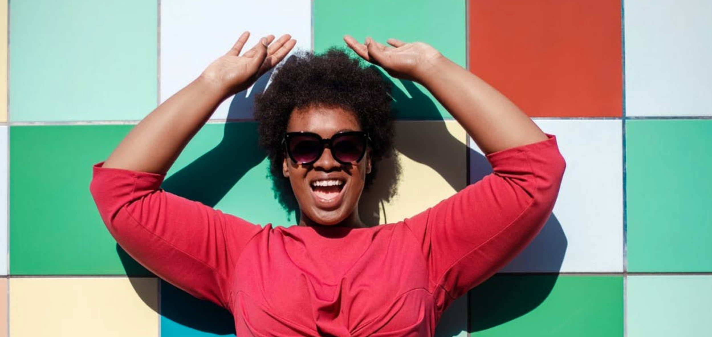 happy person raising their arms against a tiled background