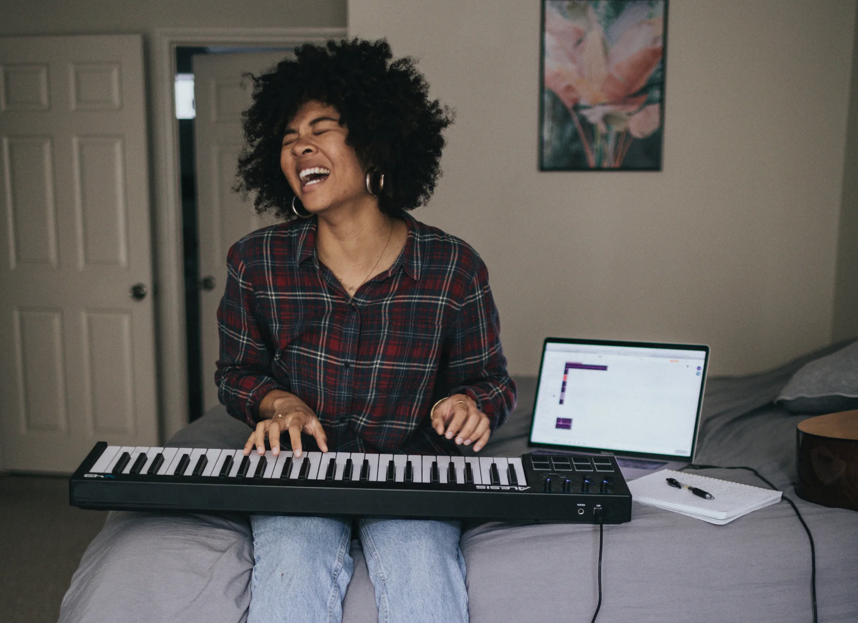 happy person playing the keyboard on a bed