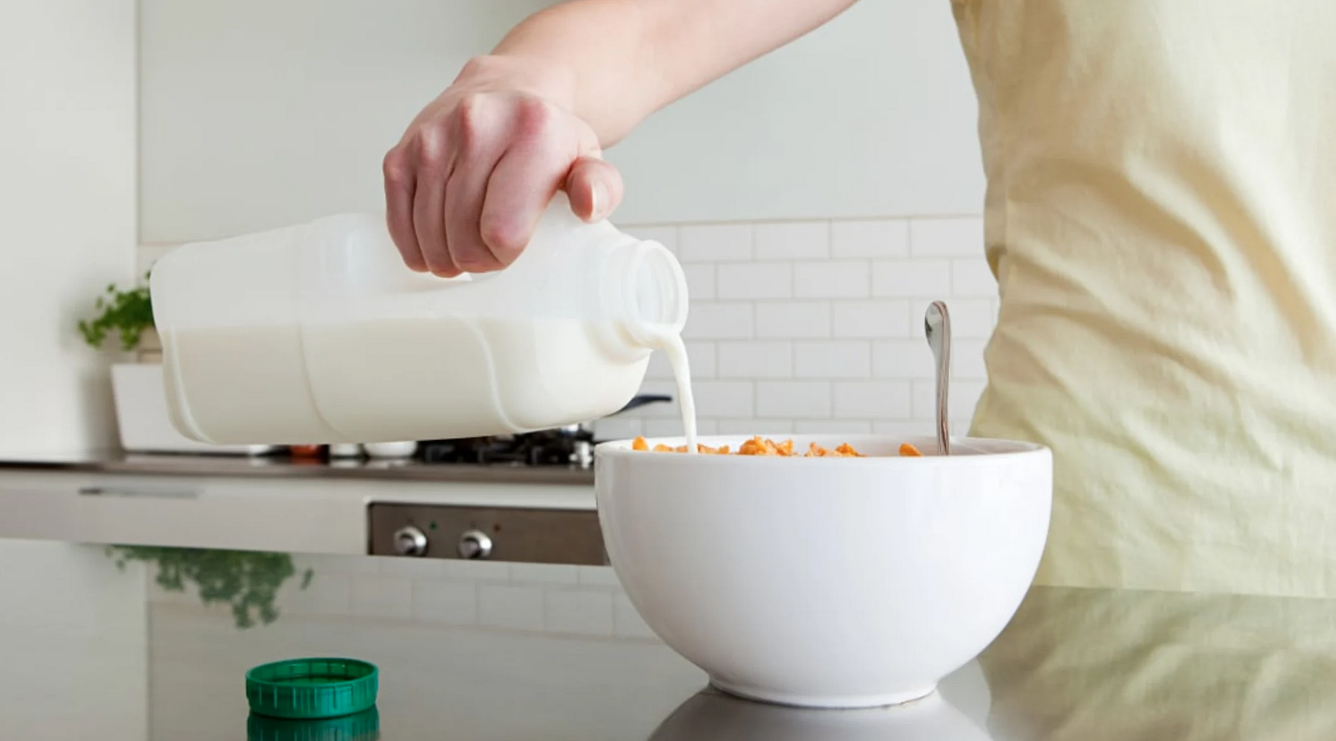 person pouring milk into a large bowl of cereral