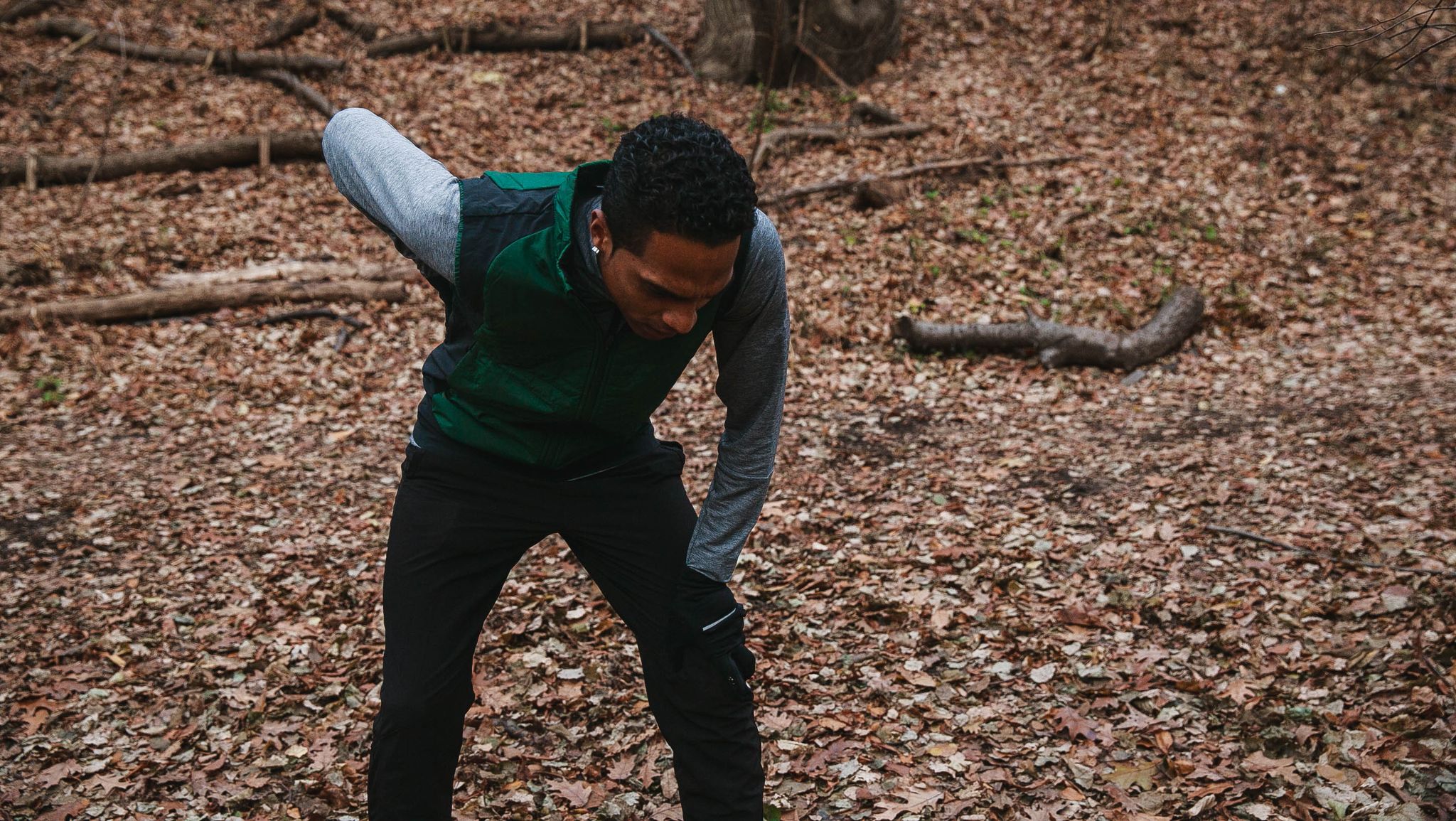 Man in running gear leaning over with a hand on his lower back