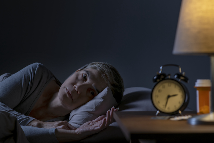 woman lying in bed staring at clock