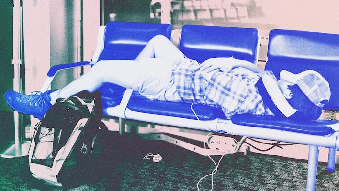 man sleeping on airport bench